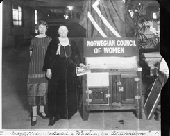 Betzy Kjelsberg og en ikke navngitt kvinne på en stand som presenterer Norwegian Council of Women (Norske kvinners nasjonalråd) på en utstilling, trolig i USAFoto: Norsk Teknisk Museum NTM C 27989<br>